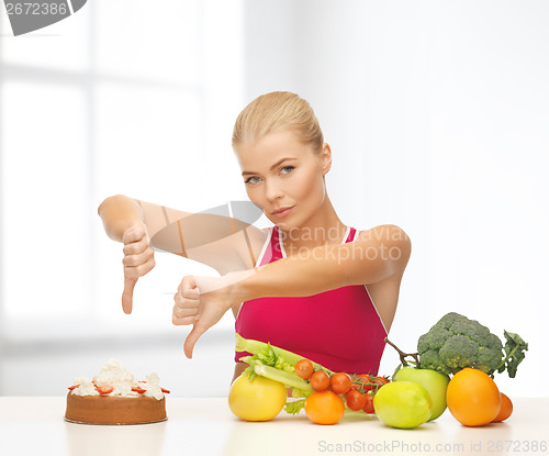 Image of woman with fruits showing thumbs down to cake