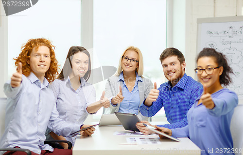 Image of smiling team with table pc and papers working