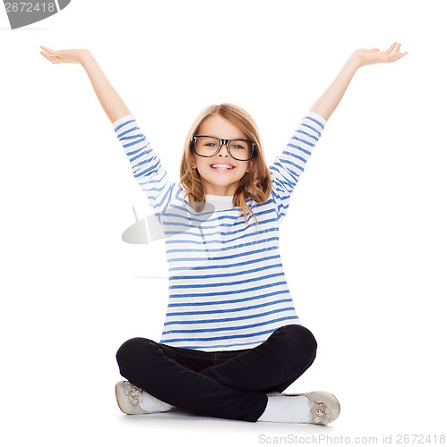 Image of smiling girl in eyeglasses sitting on floor