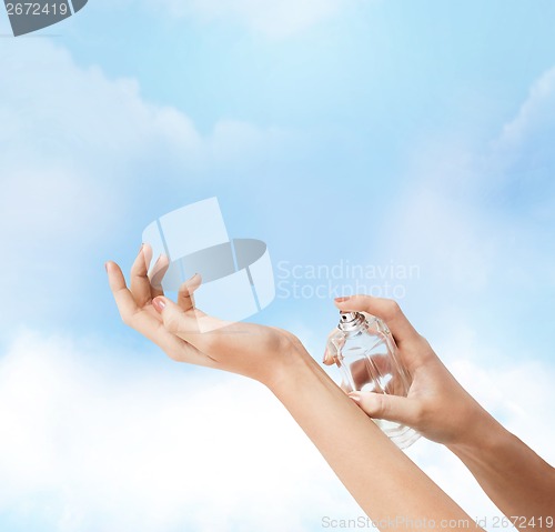 Image of woman hands spraying perfume