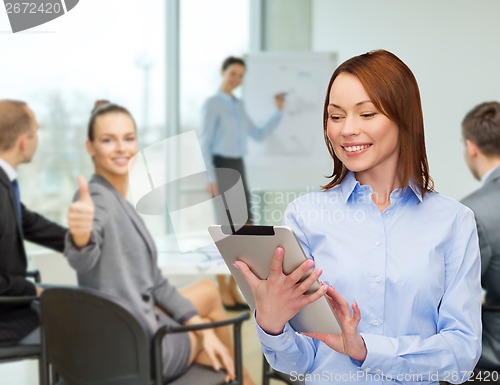 Image of smiling woman looking at tablet pc at office
