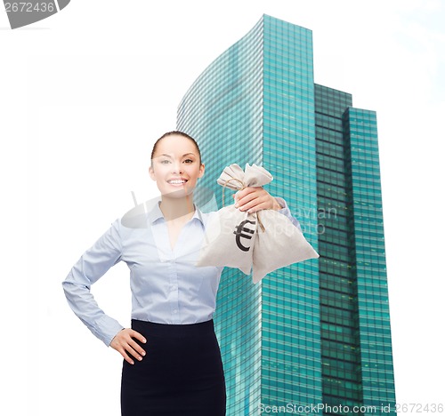 Image of young businesswoman holding money bags with euro