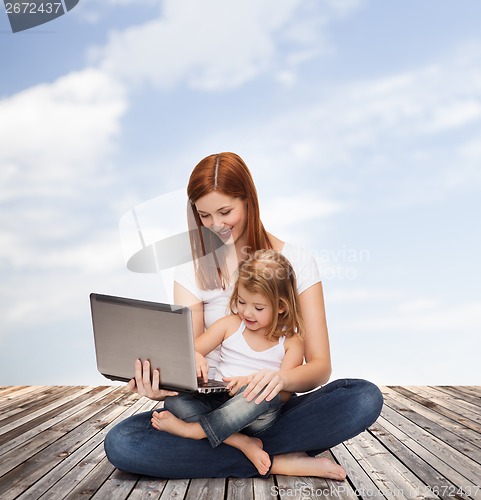 Image of happy mother with adorable little girl and laptop