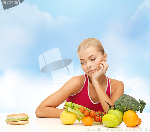 Image of doubting woman with fruits and hamburger