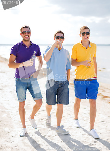 Image of male friends on the beach with bottles of drink