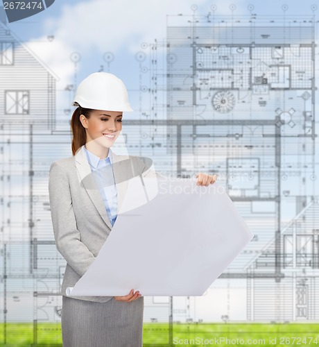 Image of smiling architect in white helmet with blueprints