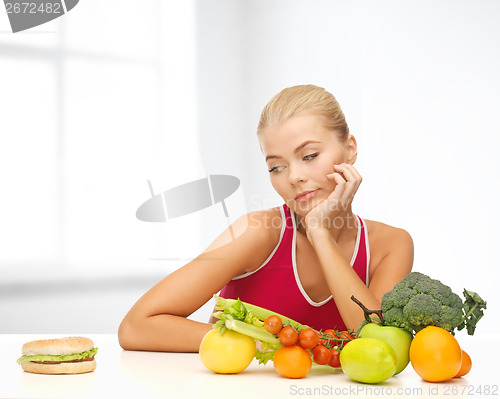 Image of doubting woman with fruits and hamburger