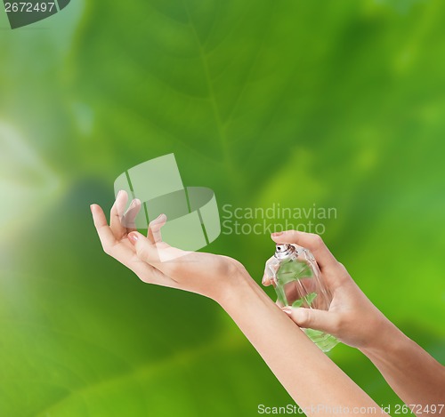 Image of woman hands spraying perfume