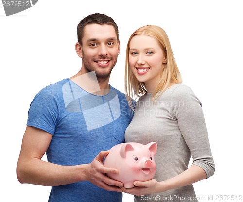 Image of smiling couple holding big piggy bank