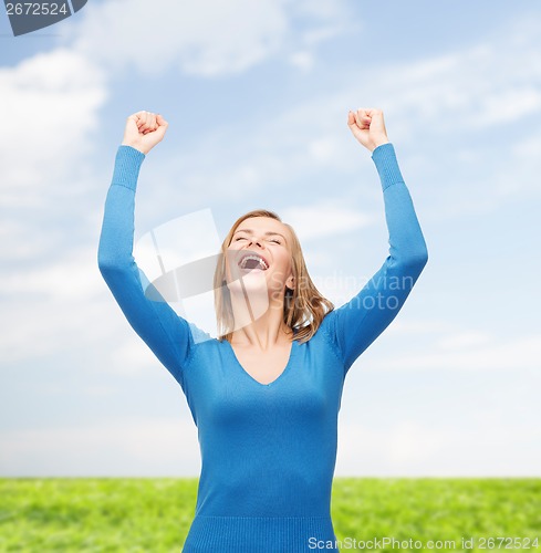 Image of laughing young woman with hands up