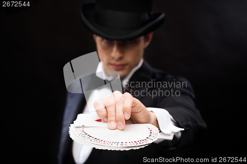 Image of magician in hat showing trick with playing cards