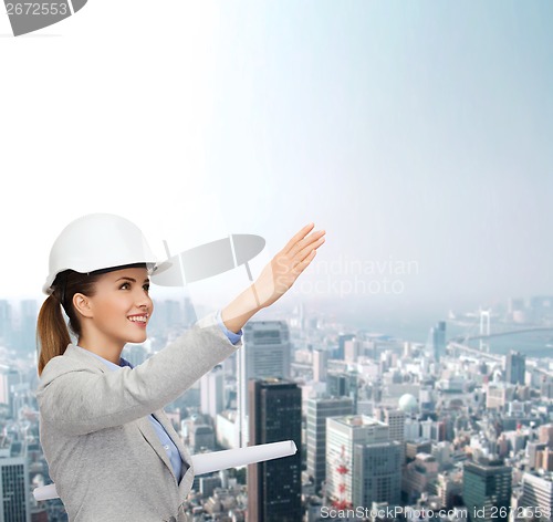 Image of smiling architect in white helmet with blueprints