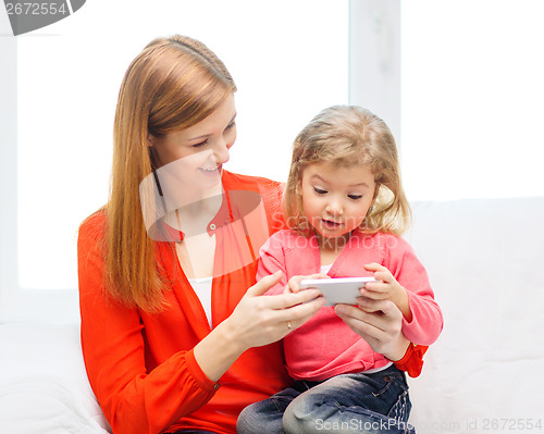 Image of happy mother and daughter with smartphone at home