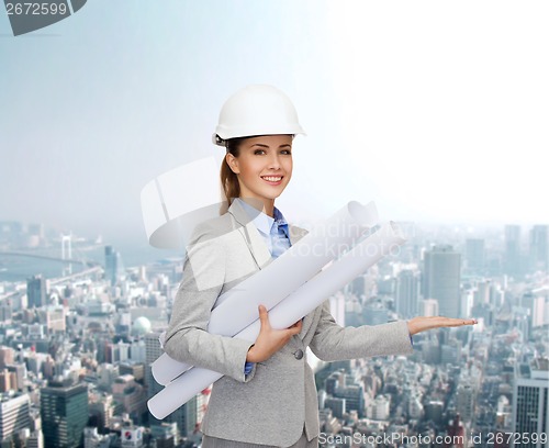 Image of smiling architect in white helmet with blueprints