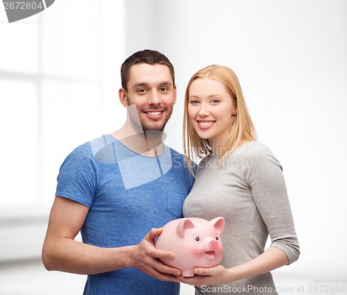 Image of smiling couple holding big piggy bank