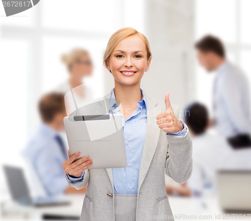 Image of smiling woman with tablet pc showing thumbs up