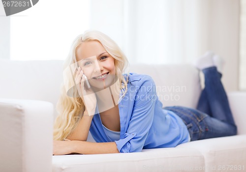 Image of smiling woman with smartphone at home