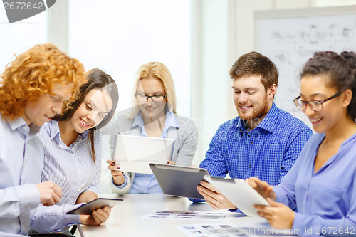 Image of smiling team with table pc and papers working