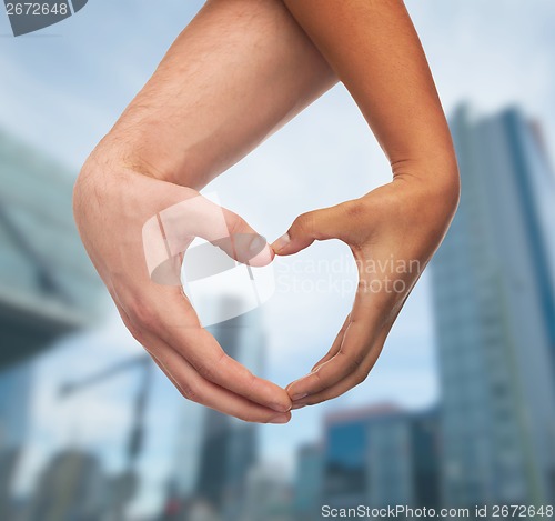 Image of woman and man hands showing heart shape