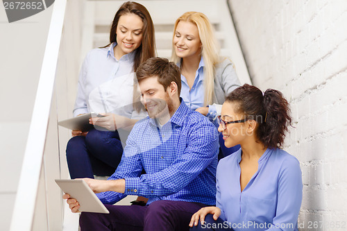 Image of team with tablet pc computer sitting on staircase