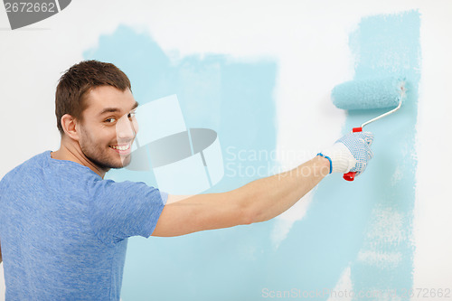 Image of smiling man painting wall at home