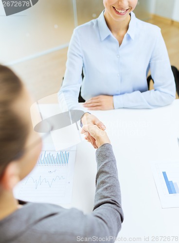 Image of two smiling businesswoman shaking hands in office