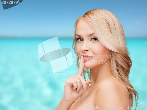 Image of beautiful young woman pointing finger to lips