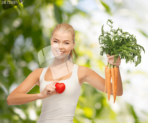 Image of smiling woman holding heart symbol and carrots