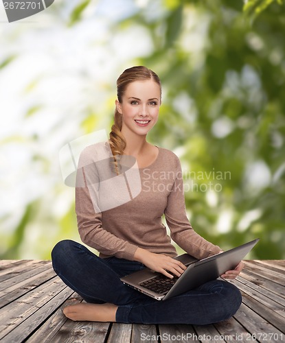 Image of young woman sitting on floor with laptop