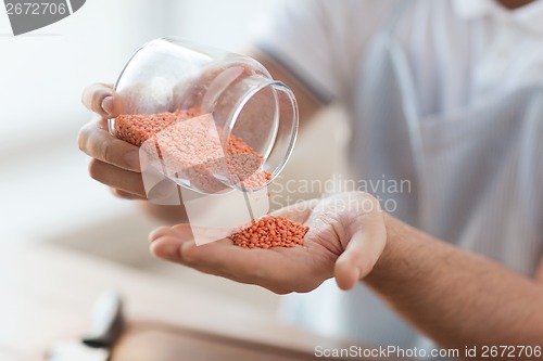 Image of close up of male emptying jar with red lentils