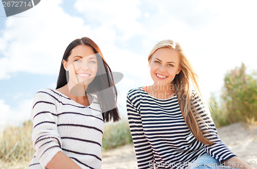 Image of smiling girlfriends having fun on the beach