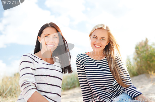 Image of smiling girlfriends having fun on the beach