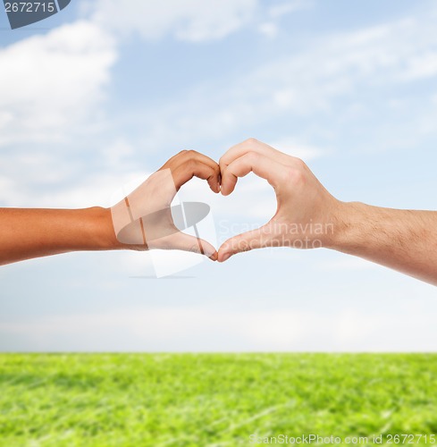 Image of woman and man hands showing heart shape