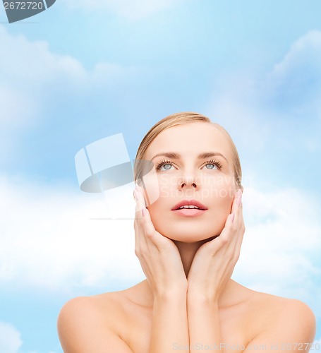 Image of beautiful woman touching her face and looking up