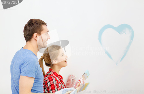 Image of smiling couple painting small heart on wall