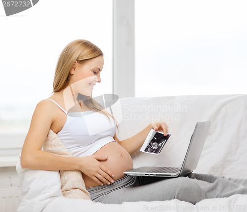 Image of smiling pregnant woman with laptop computer