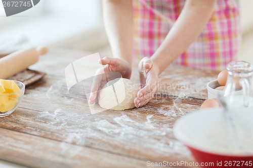 Image of close up of female hands kneading dough at home