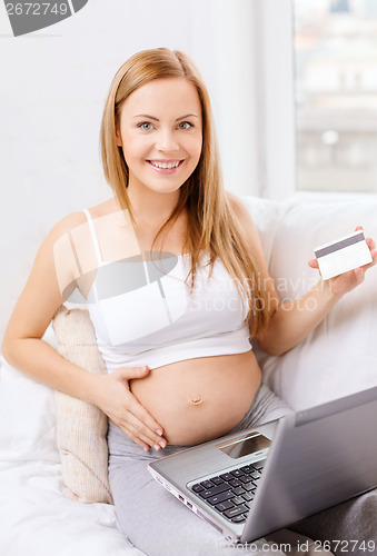 Image of smiling pregnant woman with laptop computer