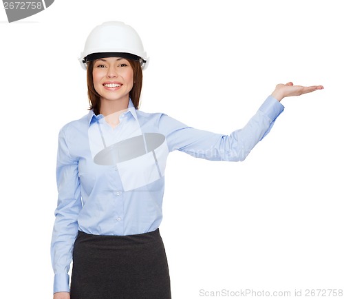 Image of businesswoman in helmet holding something on palm