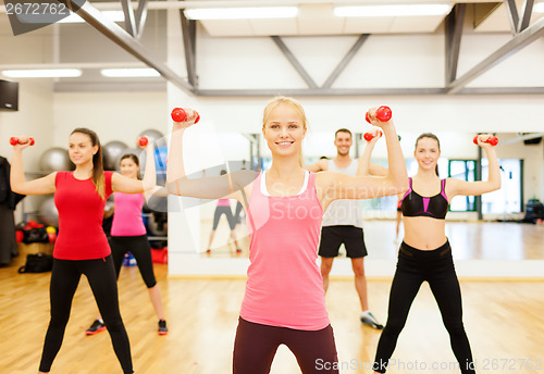 Image of group of smiling people working out with dumbbells