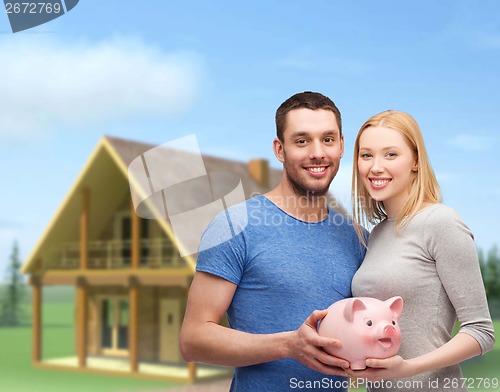 Image of smiling couple holding big piggy bank