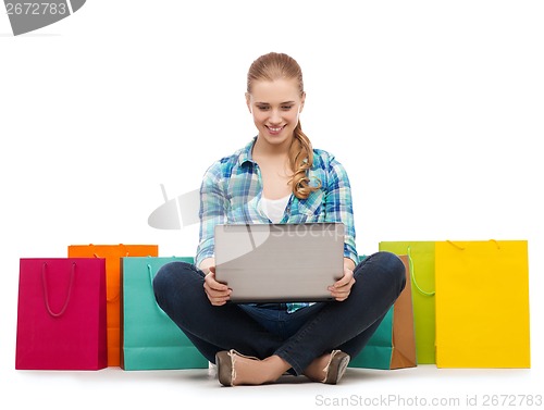 Image of smiling girl with laptop comuter and shopping bags