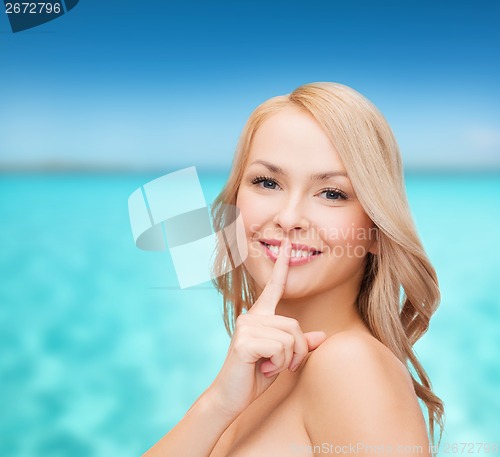 Image of beautiful young woman pointing finger to lips