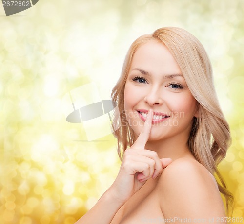 Image of beautiful young woman pointing finger to lips