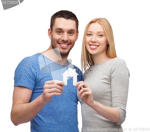 Image of smiling couple holding white paper house