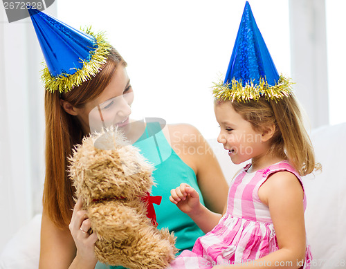 Image of mother and daughter in blue hats with teddy bear