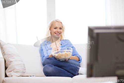 Image of young girl with popcorn watching movie at home