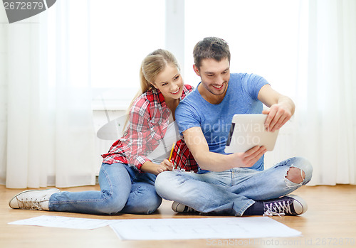 Image of smiling couple looking at tablet pc at home