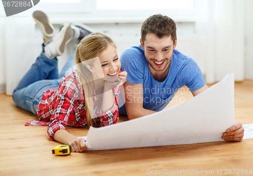 Image of smiling couple looking at blueprint at home