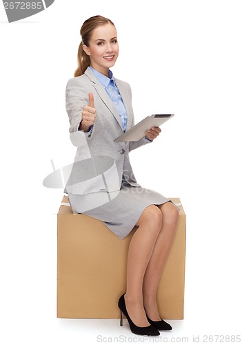 Image of woman sitting on cardboard box with tablet pc